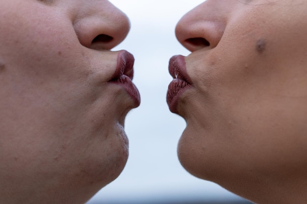 Cerca de dos mujeres frunciendo los labios a punto de besarse