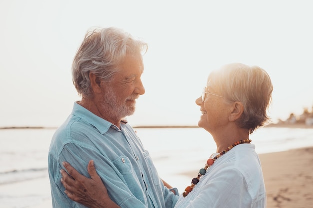 Cerca de dos personas mayores lindas y felices divirtiéndose y disfrutando juntos de un día de puesta de sol en la playa Pareja madura enamorada mirándose unos a otros