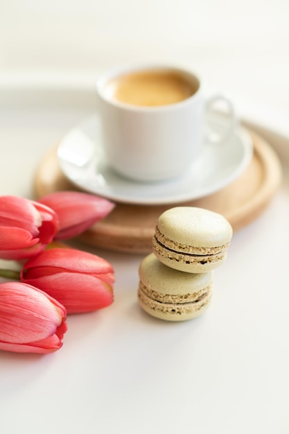 Cerca de dulces macarons franceses taza de té o café y flores de primavera sobre fondo blanco Espacio para texto