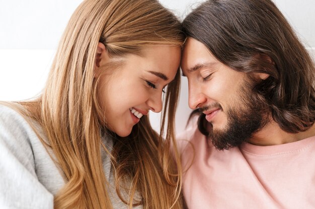 Cerca de una encantadora pareja sonriente abrazándose en casa