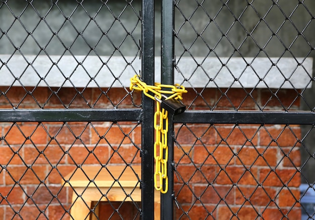 Cerca de enlace de cadena amarilla y puerta de metal con cerradura