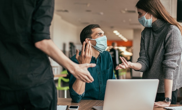 Foto de cerca. equipo de negocios con máscaras protectoras discutiendo cuestiones laborales.