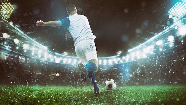 Cerca de una escena de fútbol en el partido de la noche con el jugador en un uniforme blanco y azul pateando la pelota con poder