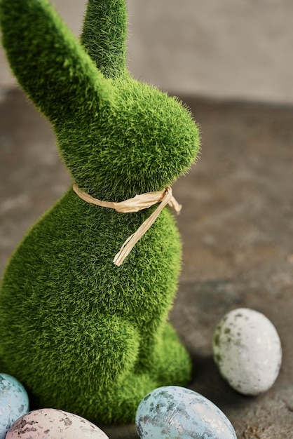 Cerca de la estatuilla de conejo de Pascua con huevos de Pascua en el fondo del césped de hierba verde Búsqueda de huevos de Pascua en el jardín Espacio de copia de enfoque selectivo