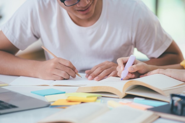 Cerca de un estudiante asiático está leyendo libros y estudiando Tutoría juntos