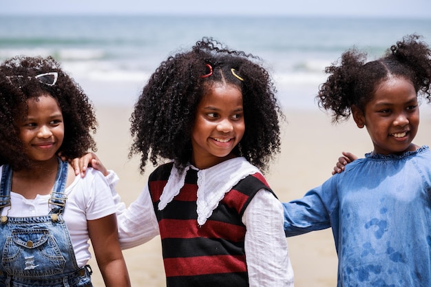 Cerca de feliz niña afroamericana en una playa tropical étnicamente diversa