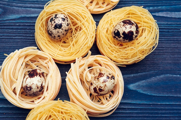 Cerca de un fettuccine de pasta italiana seca cruda en mesa de madera azul