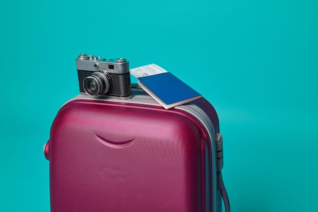 Foto de cerca. foto de estudio .cámara vintage y pasaporte con boleto y tarjeta de embarque en una maleta equipaje, aislado sobre fondo azul con espacio publicitario de copia
