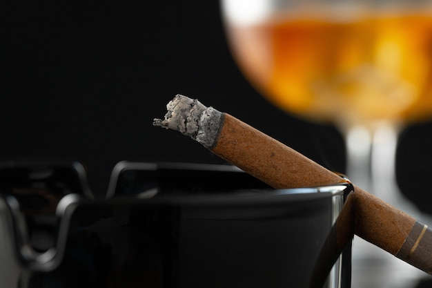 Cerca de fumar cigarros y vaso de whisky en la mesa