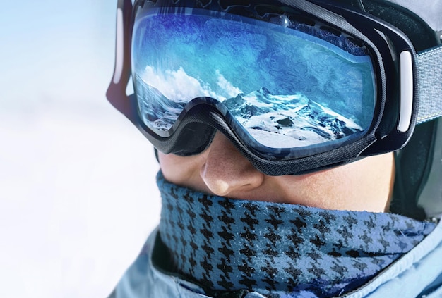 Cerca de las gafas de esquí de un hombre con el reflejo de las montañas nevadas