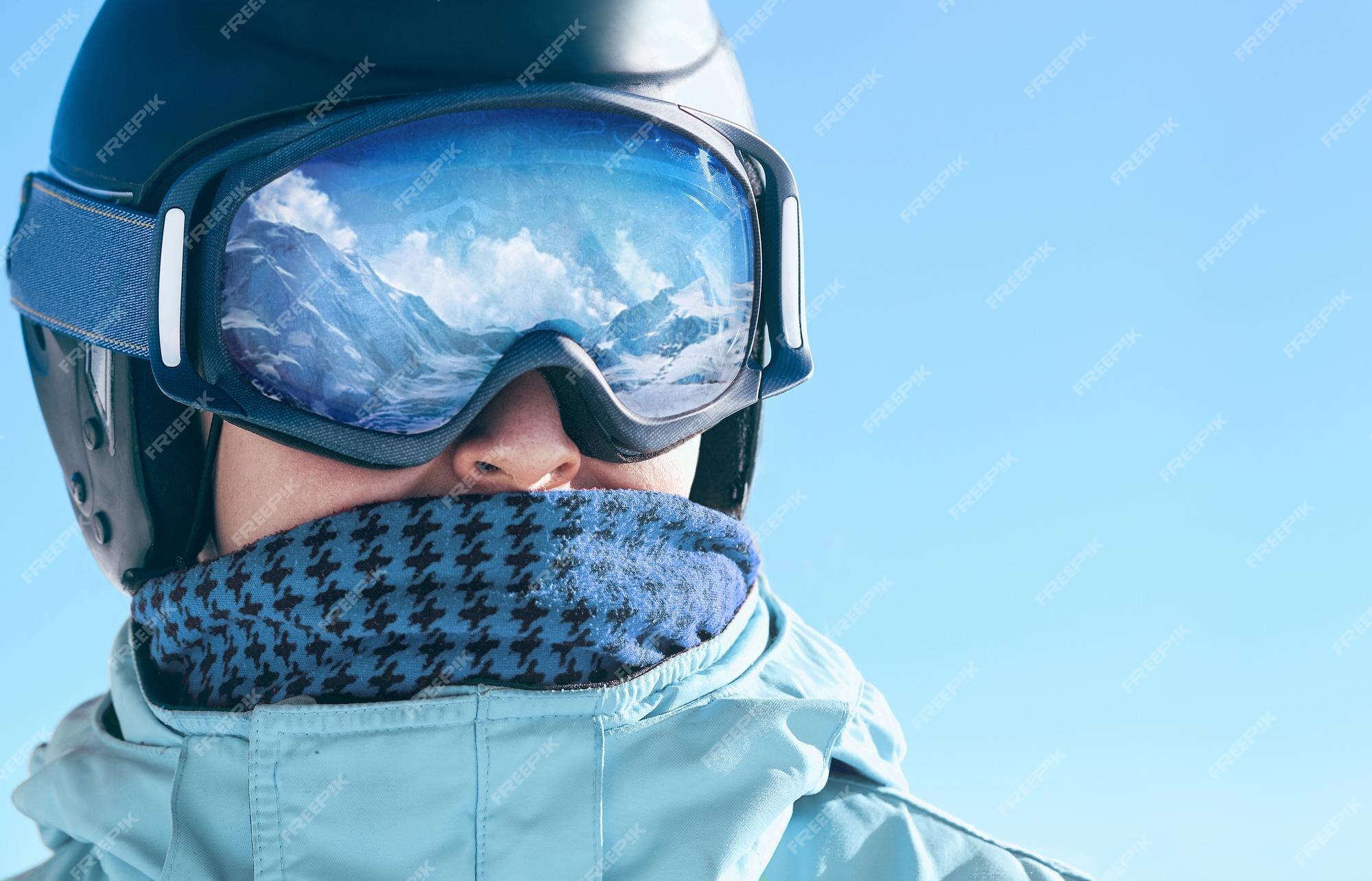 Cerca de las gafas de esquí de un hombre con el reflejo de las montañas  nevadas