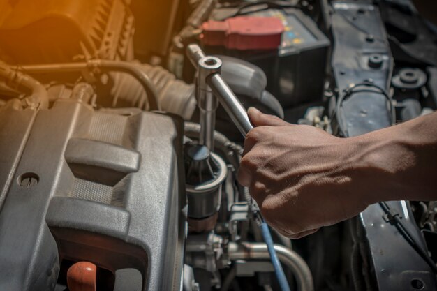 De cerca. La gente está reparando un automóvil. Use una llave y un destornillador para trabajar.