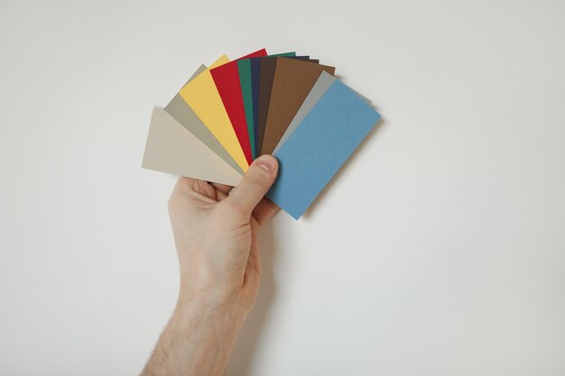 Foto cerca de hacer la mano sosteniendo muestras de color a la pared blanca mientras elige el diseño para las redecoraciones de la casa, copie el espacio