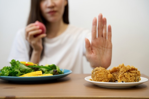 Foto cerca de la hembra usando la mano rechazar la comida chatarra sacando su pollo frito favorito.