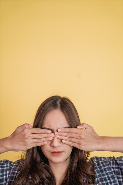 Foto cerca de una hermosa chica con el pelo largo cerrando los ojos con ambas manos con copyspace