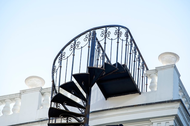 Cerca de la hermosa escalera de caracol exterior de hierro forjado en el lateral de una casa