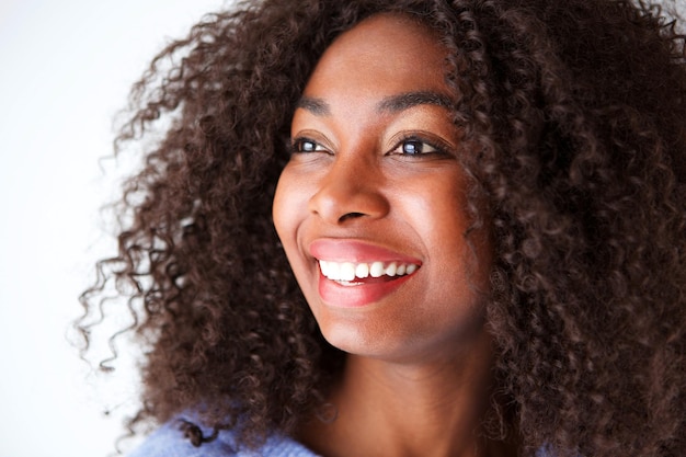 De cerca una hermosa joven africana con el cabello rizado mirando lejos sonriendo