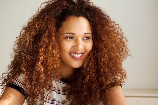 De cerca una hermosa joven con el cabello rizado sonriendo