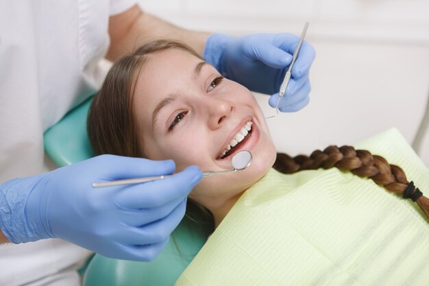 Cerca de una hermosa joven feliz sonriendo mientras el dentista examina sus dientes