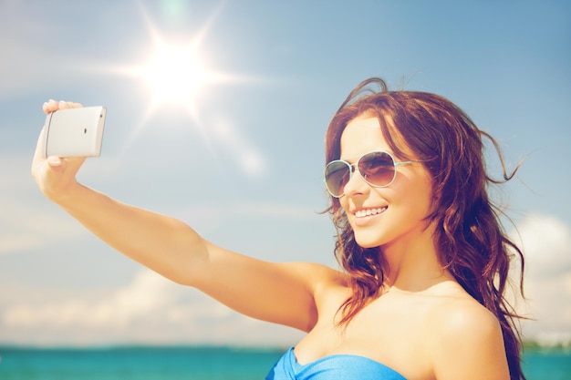 Cerca de hermosa mujer en la playa con teléfono