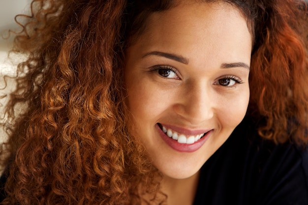 De cerca una hermosa mujer de raza mixta con el cabello rizado sonriendo