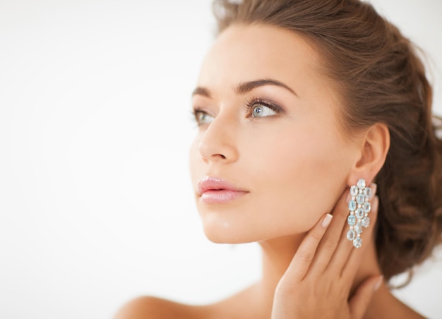 Cerca de hermosa mujer vistiendo aretes de diamantes brillantes