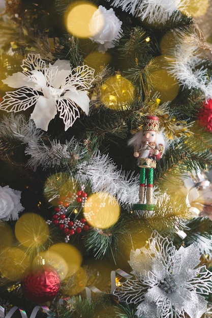 Cerca de un hermoso árbol de navidad con adornos de plata y rojo blanco y flores de nochebuena se centran en el cascanueces para su proyecto de navidad