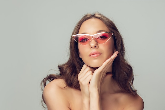 Cerca del hermoso rostro femenino, labios con maquillaje elegante brillante aislado sobre fondo gris de estudio