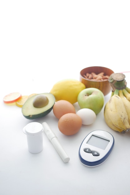 Foto cerca de herramientas de medición para diabéticos y frutas frescas sobre fondo blanco.