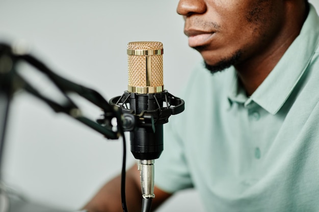 Cerca del hombre afroamericano hablando al micrófono mientras graba un podcast en casa
