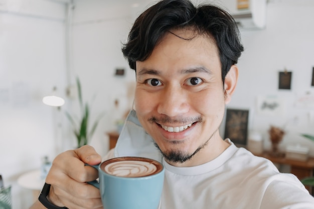 Cerca del hombre asiático selfie él mismo bebe café caliente