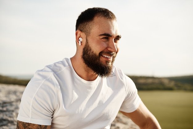 Cerca de un hombre atleta escuchando música mientras da un paseo por el campo