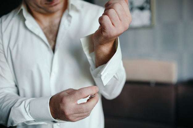 cerca del hombre en camisa vestirse y ajustar la corbata en el cuello en casa.