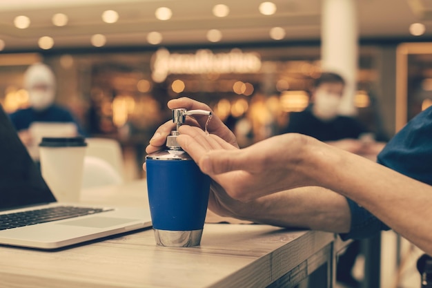 De cerca. un hombre desinfectando sus manos sentado en una mesa en un café. foto con un espacio de copia