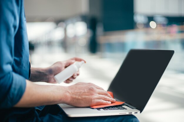 De cerca. hombre limpiando el polvo del teclado de la computadora portátil. concepto de protección de la salud