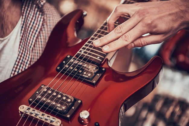 De cerca. El hombre muestra al cliente en cuerdas de guitarra eléctrica