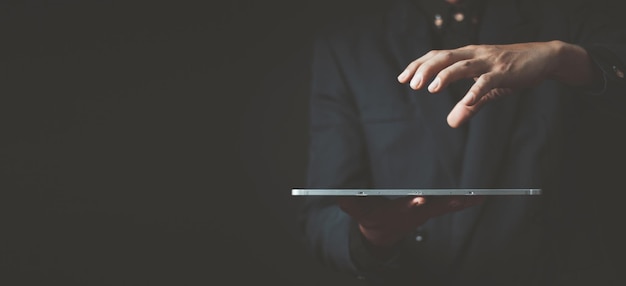 Cerca de un hombre de negocios con traje azul usando una computadora de tableta