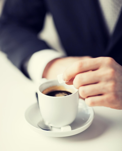 Cerca del hombre poniendo azúcar en el café