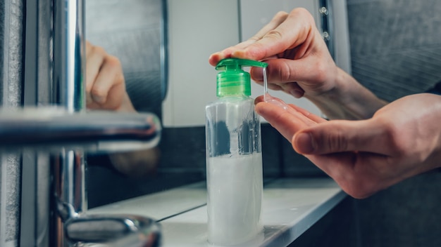 De cerca. hombre presionando el dispensador con jabón bactericida. concepto de prevención de enfermedades infecciosas.