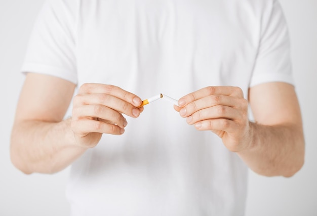 Cerca del hombre rompiendo el cigarrillo con las manos