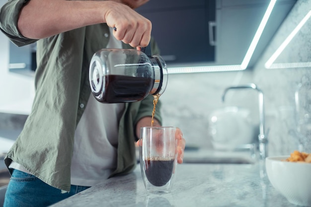 Cerca del hombre sirviendo café por la mañana