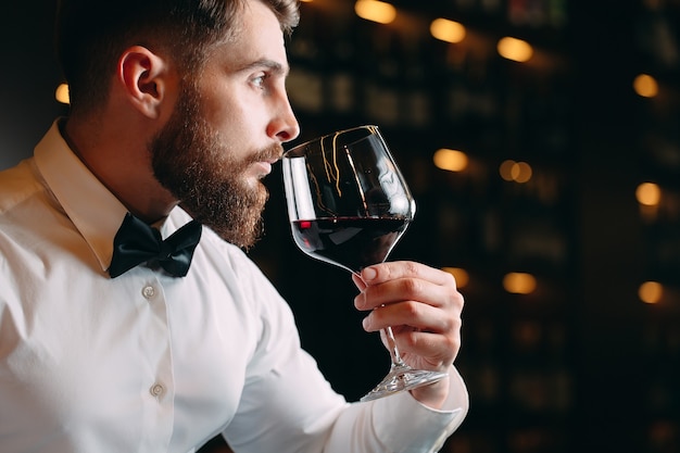 Cerca del hombre sommelier oliendo vino en vidrio