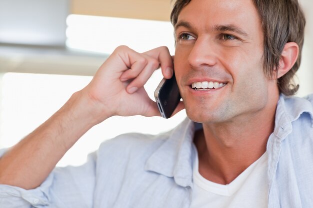 Cerca de un hombre sonriente haciendo una llamada telefónica