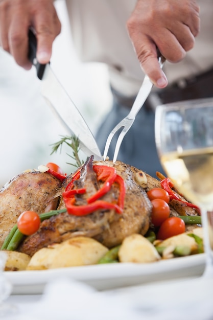 Cerca de un hombre tallando el pollo asado