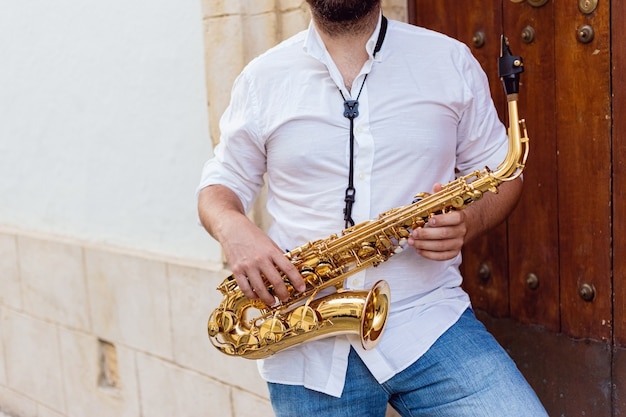 Cerca de un hombre tocando apasionadamente su saxofón en la puerta de un edificio en la calle
