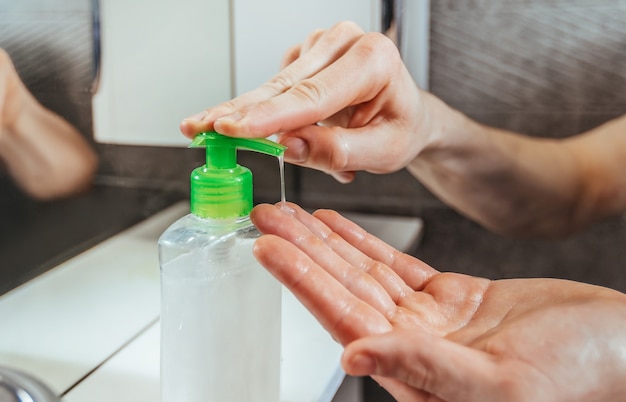 De cerca. hombre usando un dispensador con jabón bactericida.