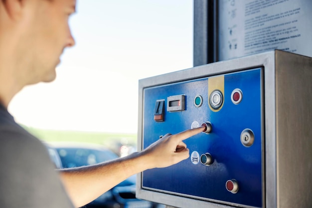 Cerca del hombre usando una máquina de monedas de autoservicio en el lavado de autos