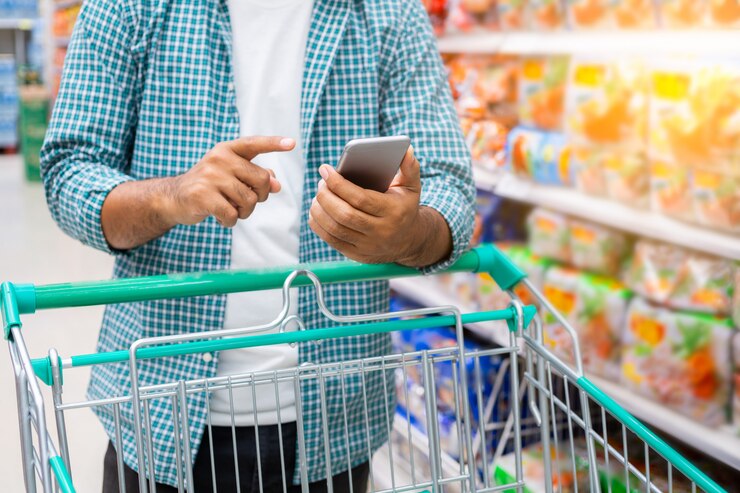 Cerca de un hombre usando un teléfono inteligente y de compras en un supermercado, concepto de compras