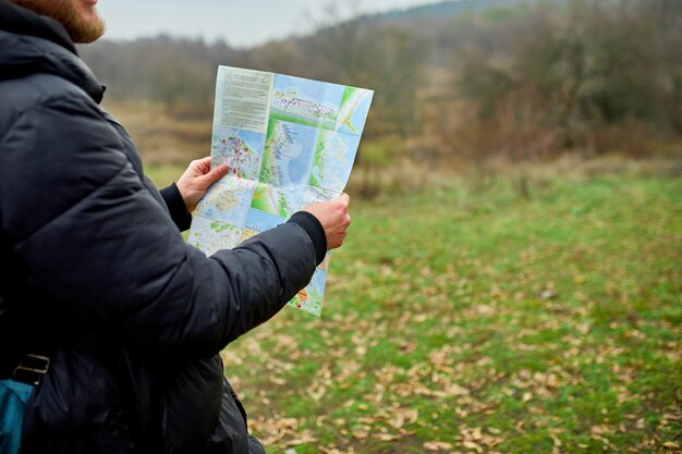 Cerca del hombre viajero con mochila con mapa en mano sobre un fondo de montañas, río de la naturaleza