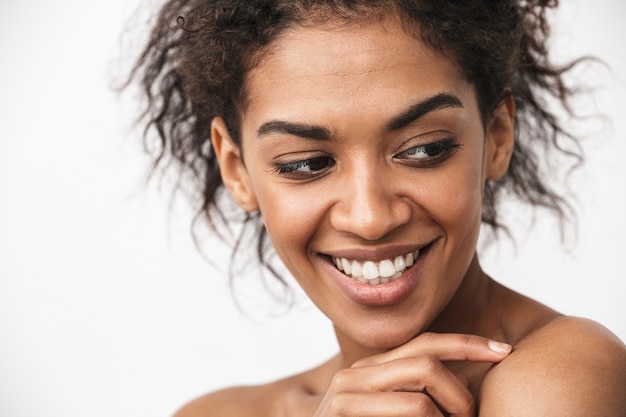 Cerca de una joven y bella mujer africana en topless posando sobre blanco